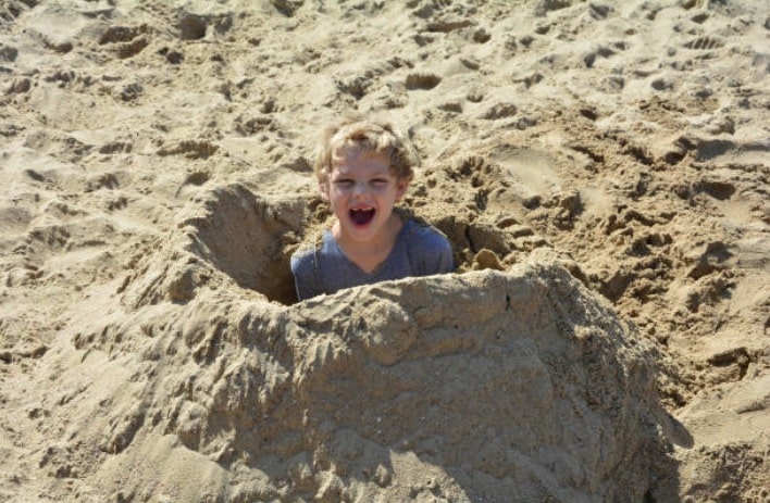 enfant sable enterrer jeu plage