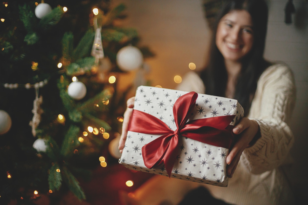 jeune femme qui tend un cadeau à la caméra